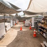 Chantier extérieur bien organisé, avec zones distinctes, matériaux protégés sous bâches et outils rangés, ambiance professionnelle sous lumière naturelle.