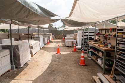 Chantier extérieur bien organisé, avec zones distinctes, matériaux protégés sous bâches et outils rangés, ambiance professionnelle sous lumière naturelle.