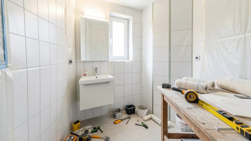 Petite salle de bain en rénovation, outils rangés proprement, meuble vasque simple et ambiance de chantier lumineuse.