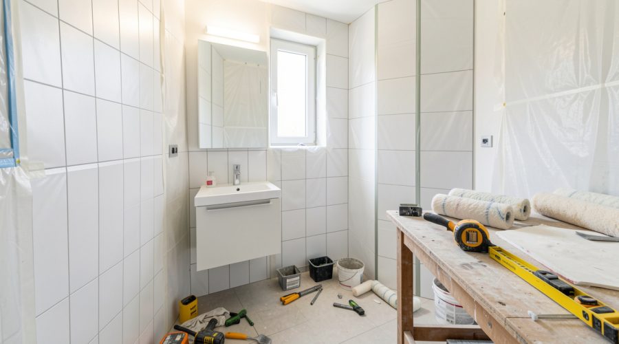 Petite salle de bain en rénovation, outils rangés proprement, meuble vasque simple et ambiance de chantier lumineuse.