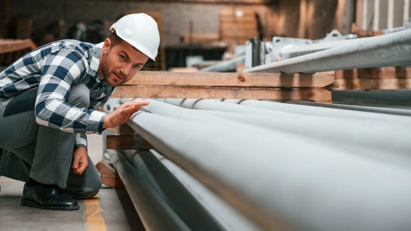 Couvreur utilisant une plieuse à zinc pour façonner une feuille de métal sur un chantier.